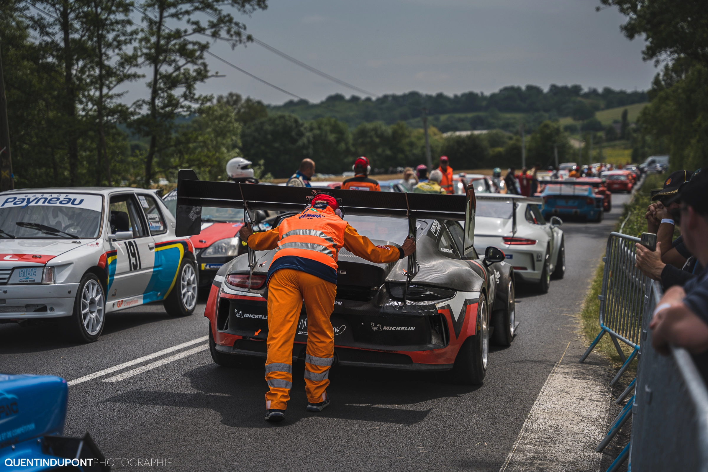 Bénévole qui pousse une voiture lors de la Course de Côte de la Pommeraye